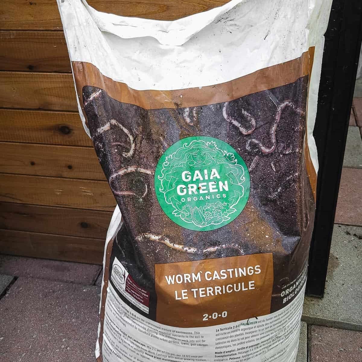 A large bag of Gaia Green worm castings in front of a raised bed.