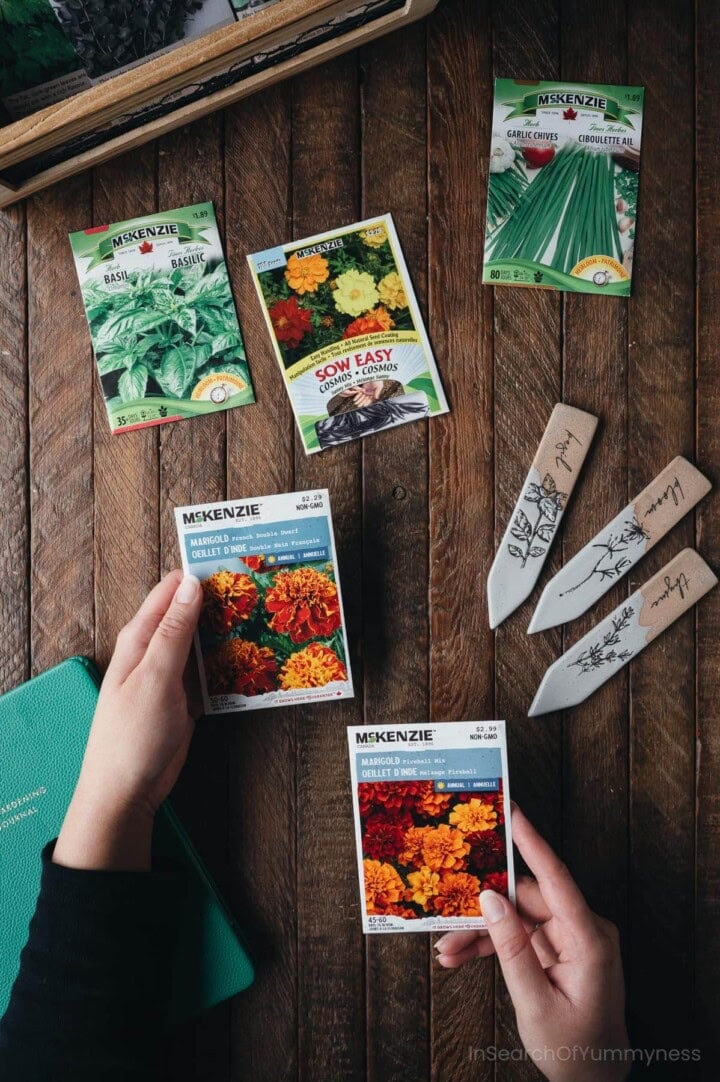 A pair of hands holding colourful seed packets from McKenzie seeds.