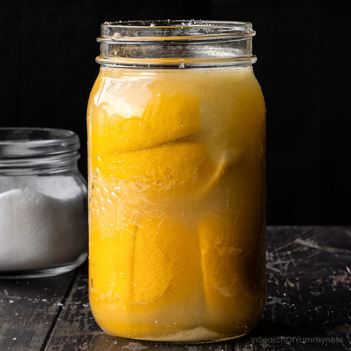 A large mason jar full of salted lemons and lemon juice to turn into preserved lemons.