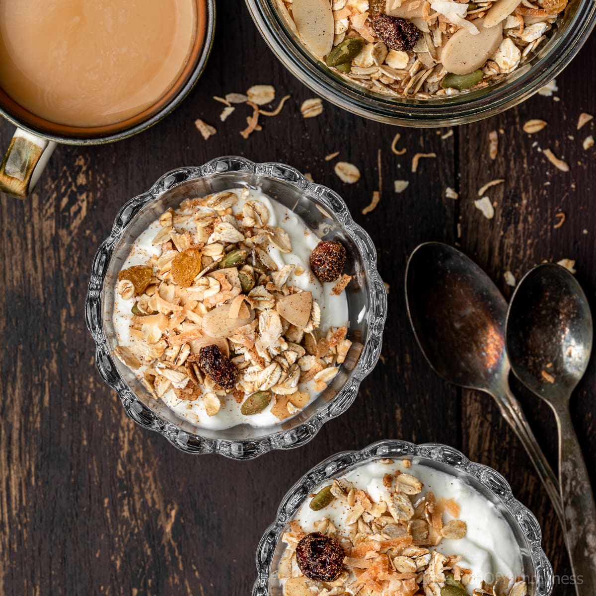 Toasted muesli yogurt parfaits next to a Weck jar with more muesli, next to a cup of tea.