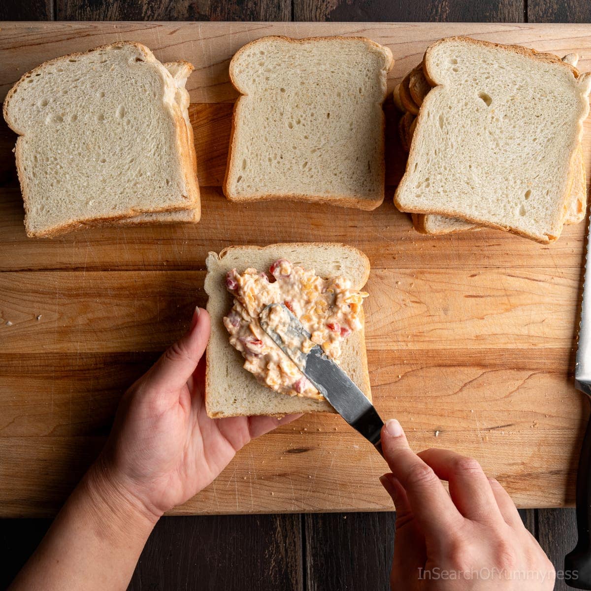 Spreading pimento cheese onto a slice of bread with an offset spatula.