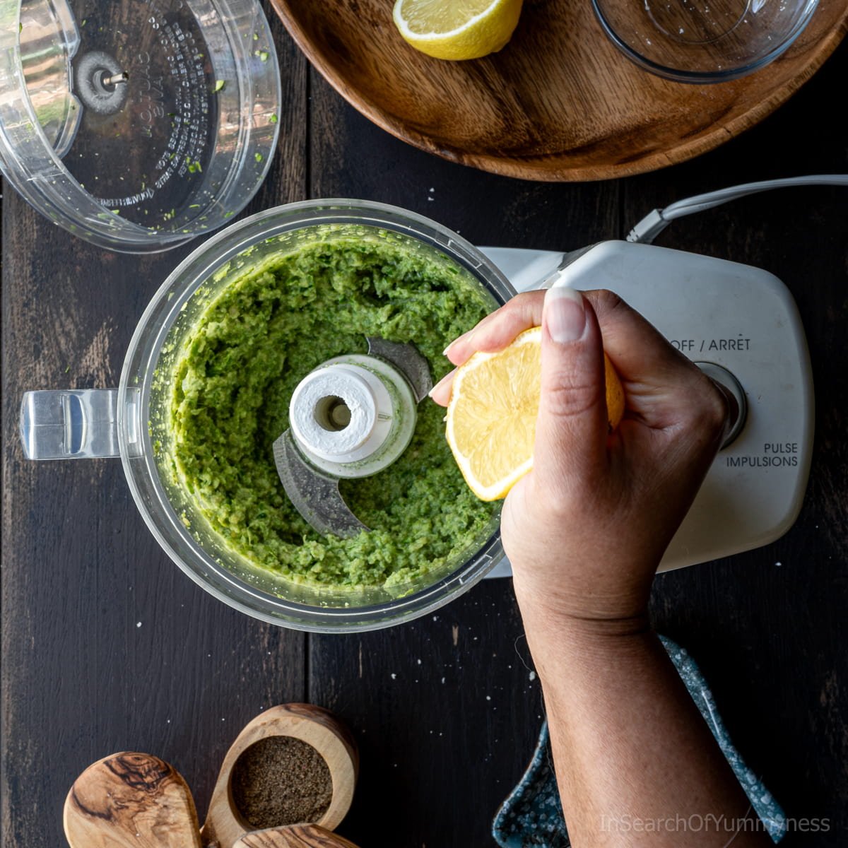 Adding lemon juice to garlic scape pesto in a food processor.