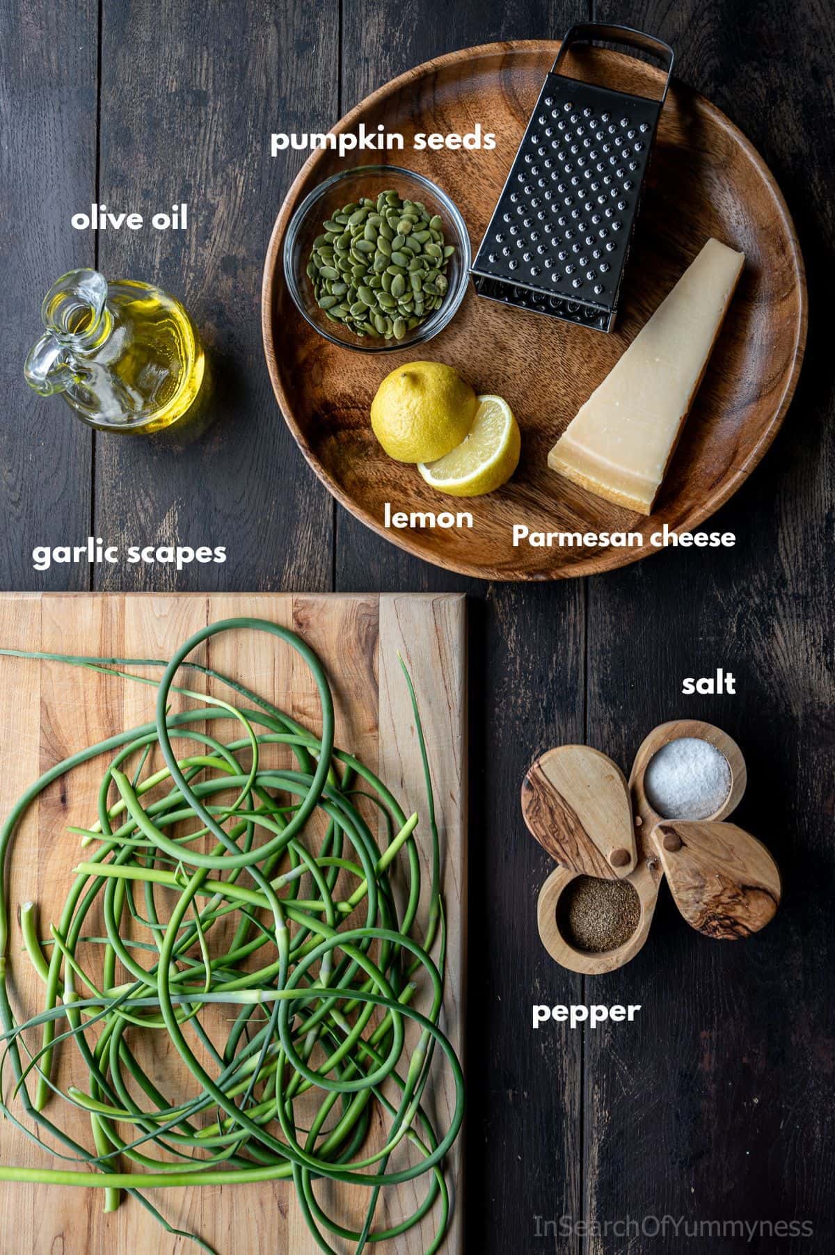The ingredients for garlic scape pesto on a table with a box grater.