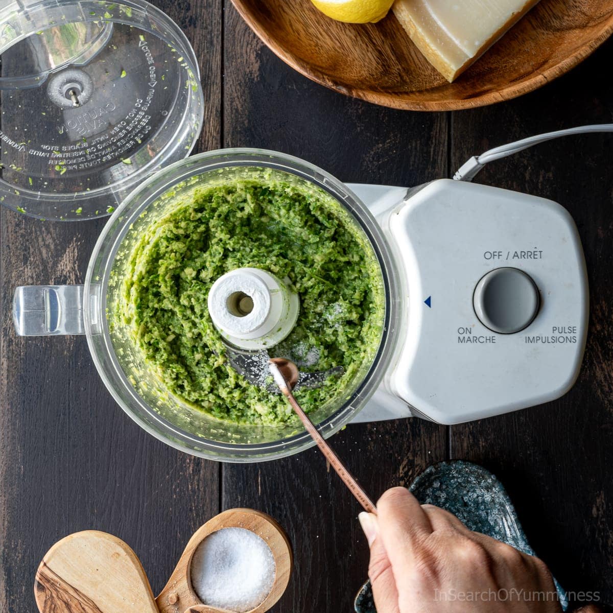 Adding salt to garlic scape pesto mixture in a food processor.