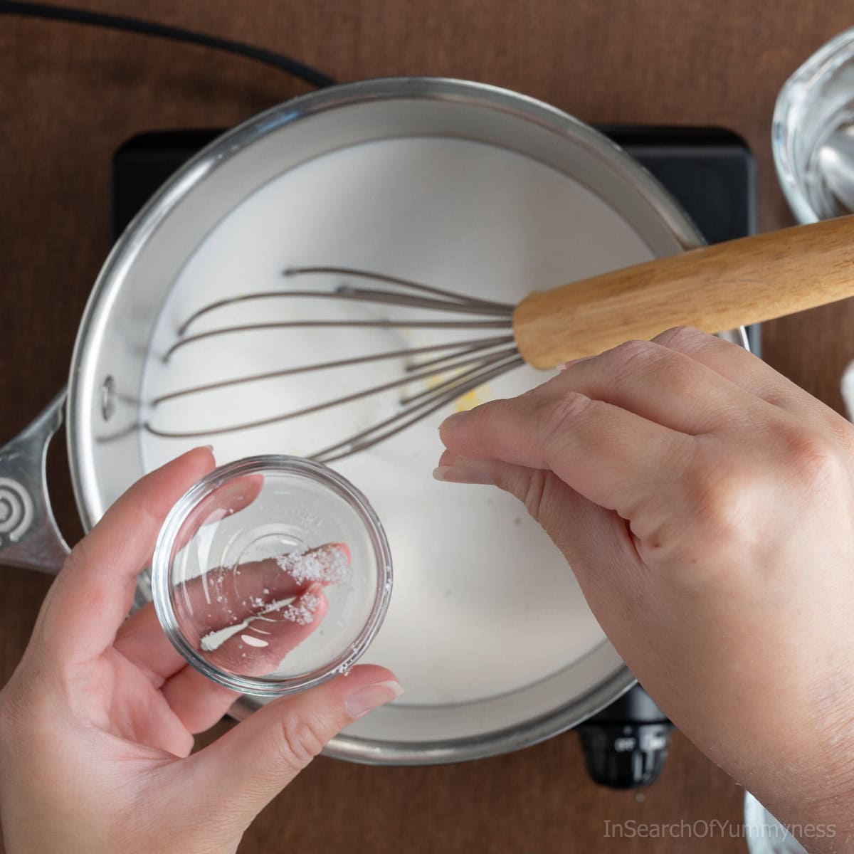 Adding a pinch of salt to the coconut milk in a saucepan.