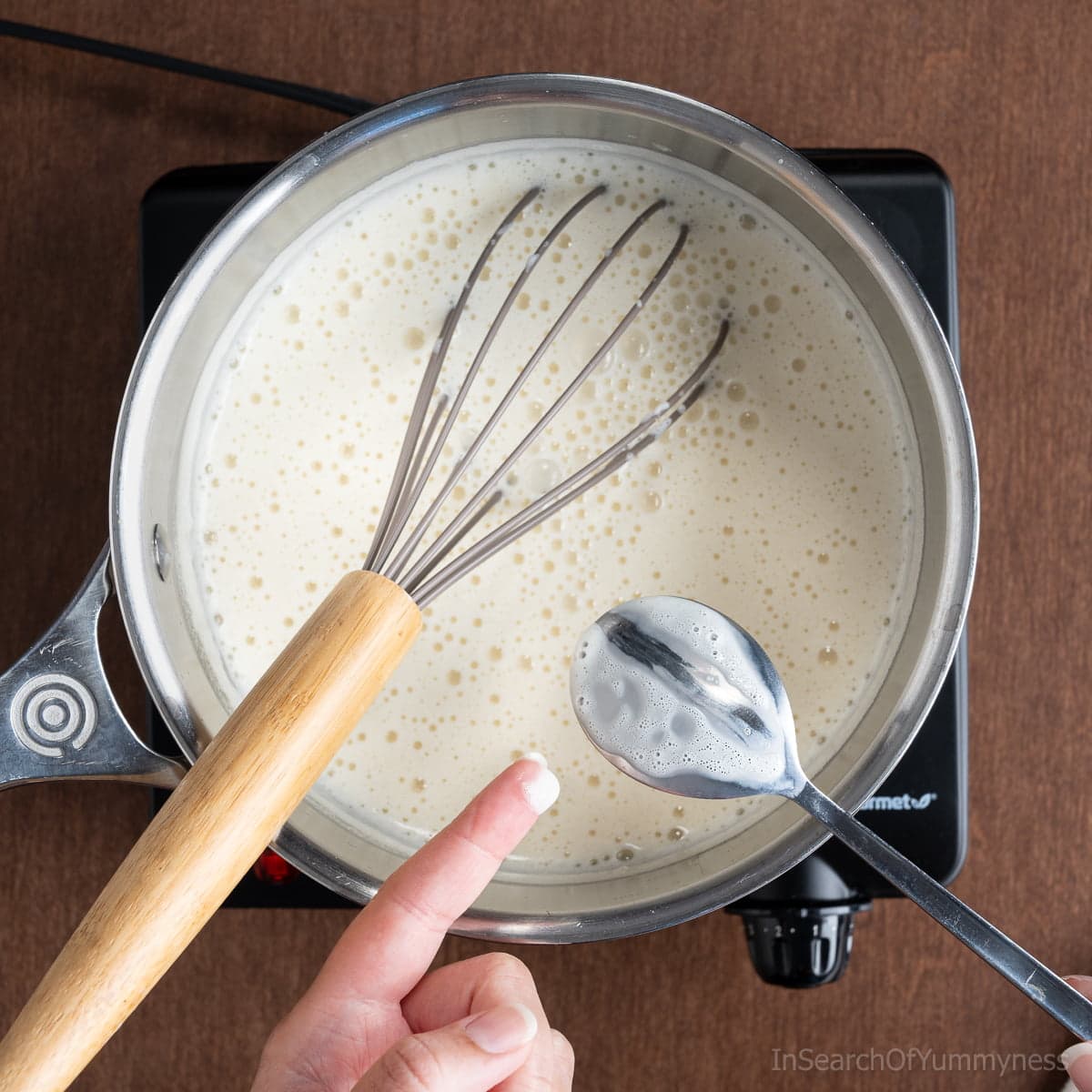 Testing the thickness of the ice cream base by dragging a finger across the back of a metal spoon.
