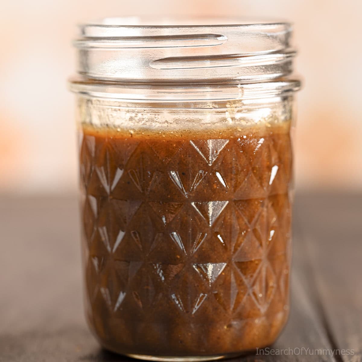 A small glass jar filled with homemade balsamic Dijon vinaigrette, showing its rich brown color