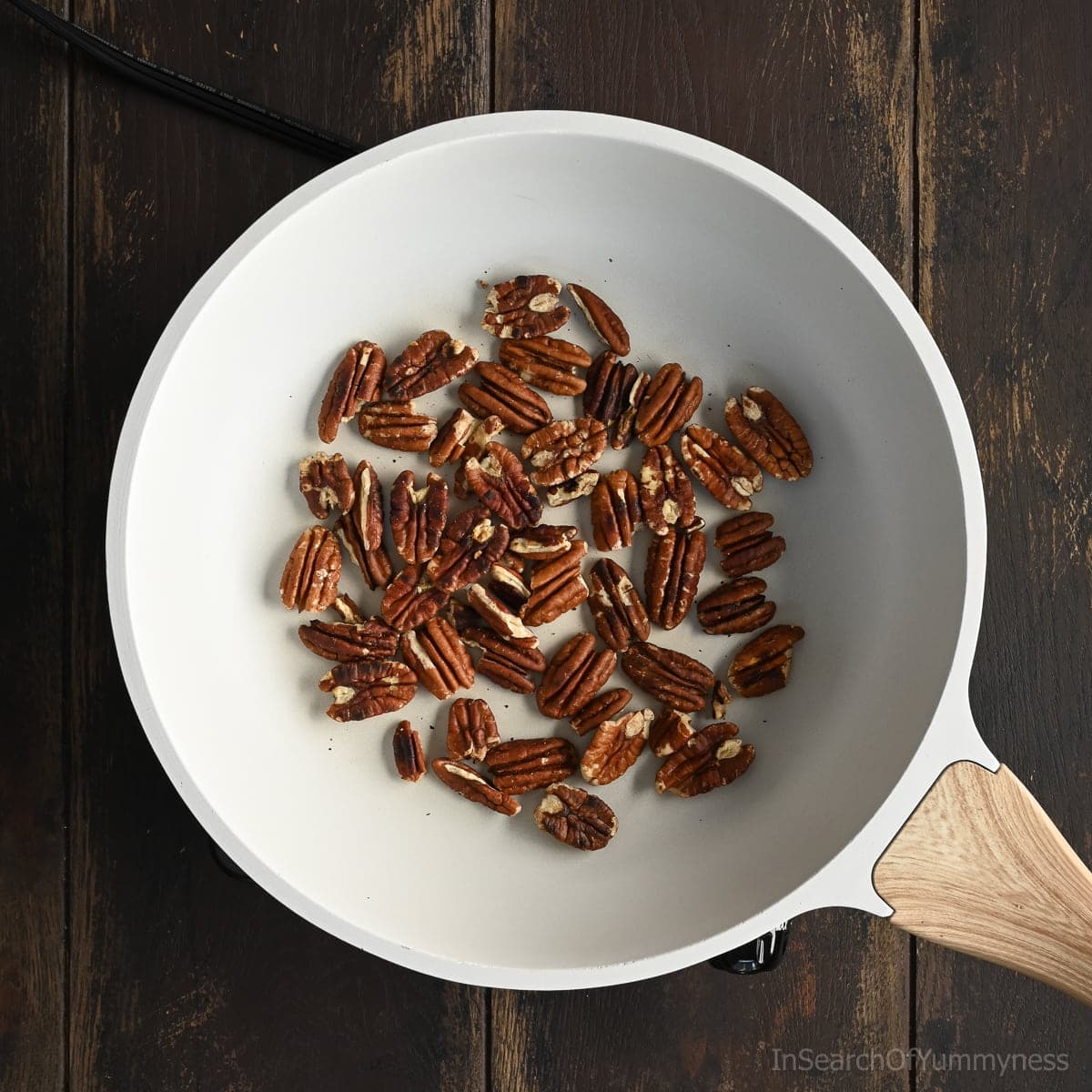 Roasted pecans in a white skillet for delicious snack, dessert topping or baking ingredient.
