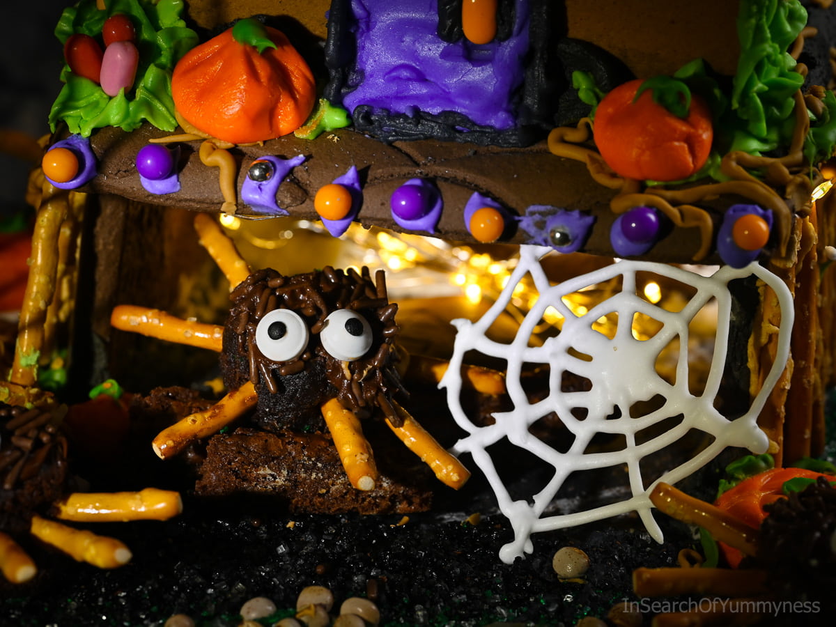 A decorated spider brownie inside the garage of a Haunted gingerbread house, next to a spider web.