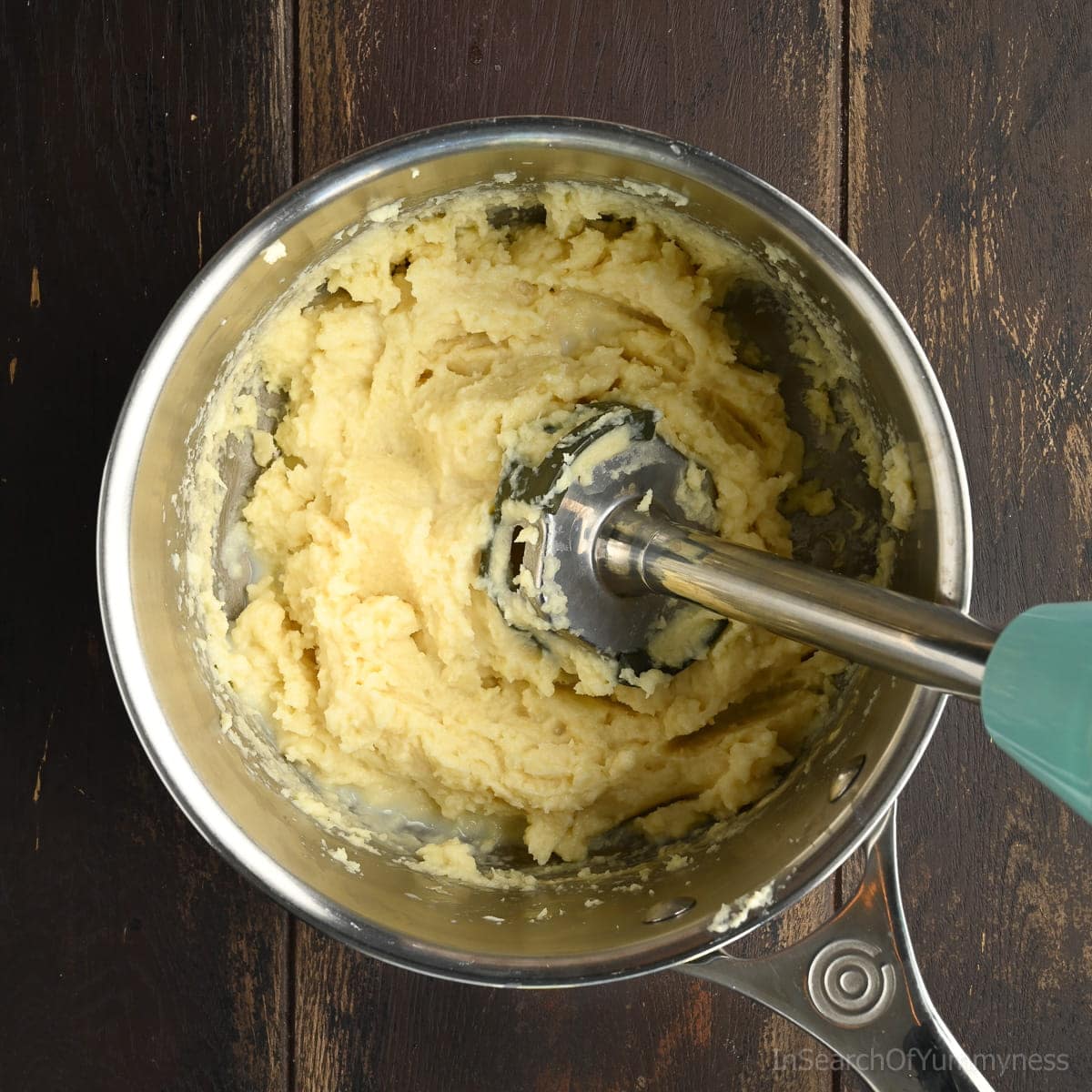 Mashing parsnips in a stainless steel pot with an immersion blender.