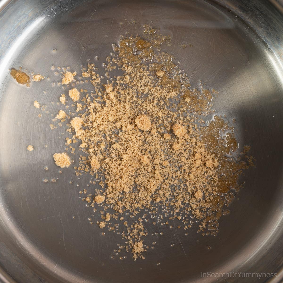 Brown sugar slowly caramelizing in hot oil in a stainless steel pot.