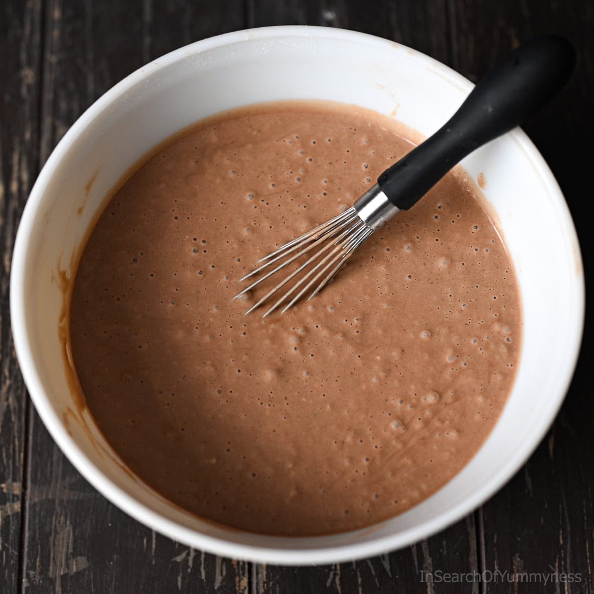 A large mixing bowl full of Nutella pancake batter with a whisk sitting in it.