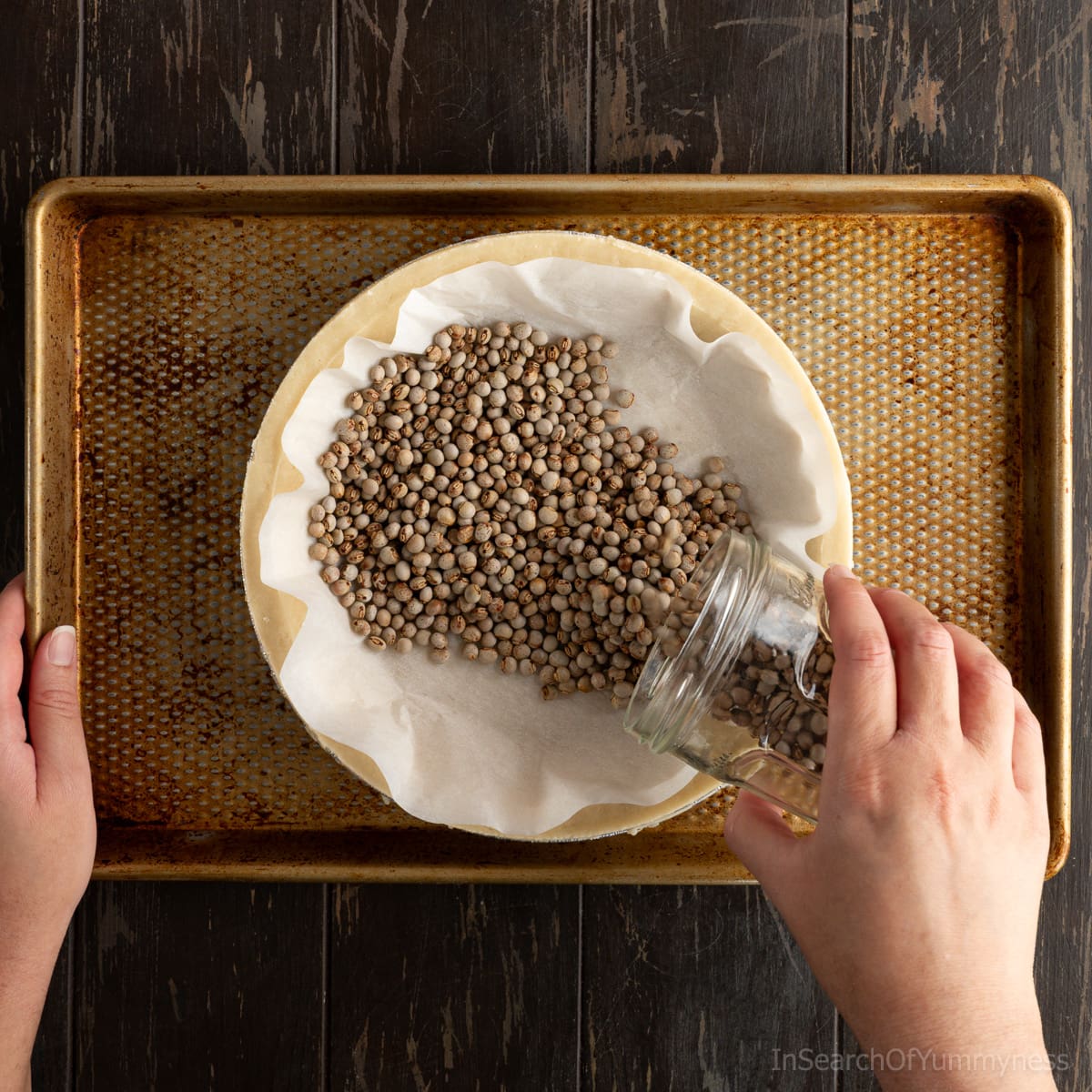 Adding pie weights (dried beans) to an unbaked pie shell.