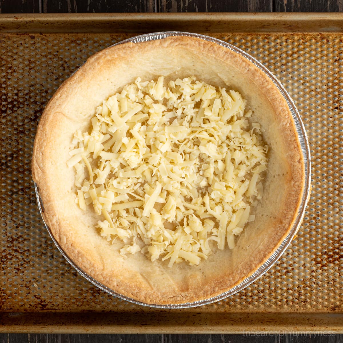 An even layer of cheddar cheese inside a baked pie shell.