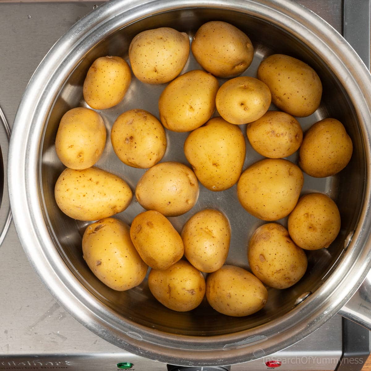 Yellow new potatoes cooking in a saucepan on the stovetop.