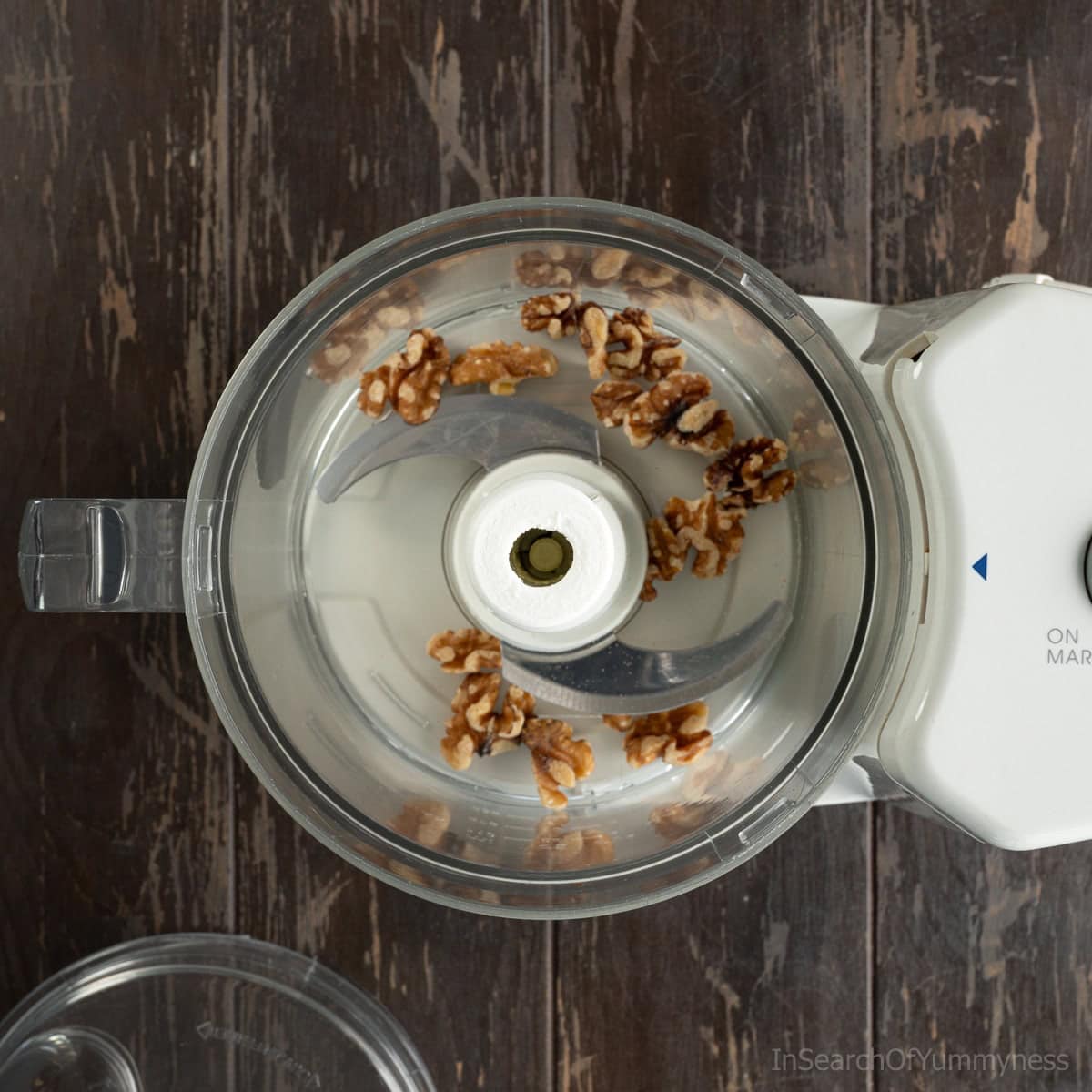 Adding walnuts to the food processor work bowl.