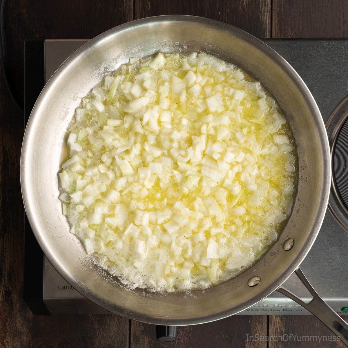 Finely chopped onions sweating in butter in a stainless steel skillet.