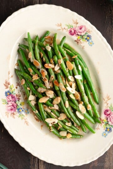 A vintage floral plate with green beans almondine; a dish made with buttery sautéed green beans topped with toasted almonds.