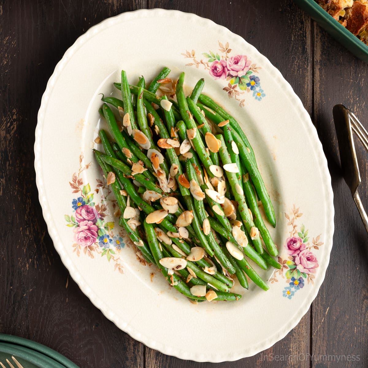 A vintage floral plate with green beans almondine; a dish made with buttery sautéed green beans topped with toasted almonds.