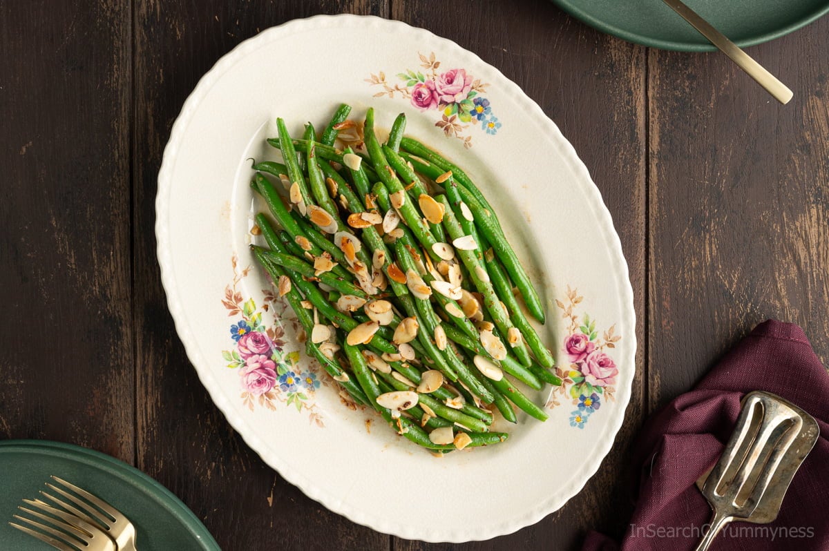 A vintage floral plate with green beans almondine; buttery sautéed green beans topped with toasted slivered almonds.