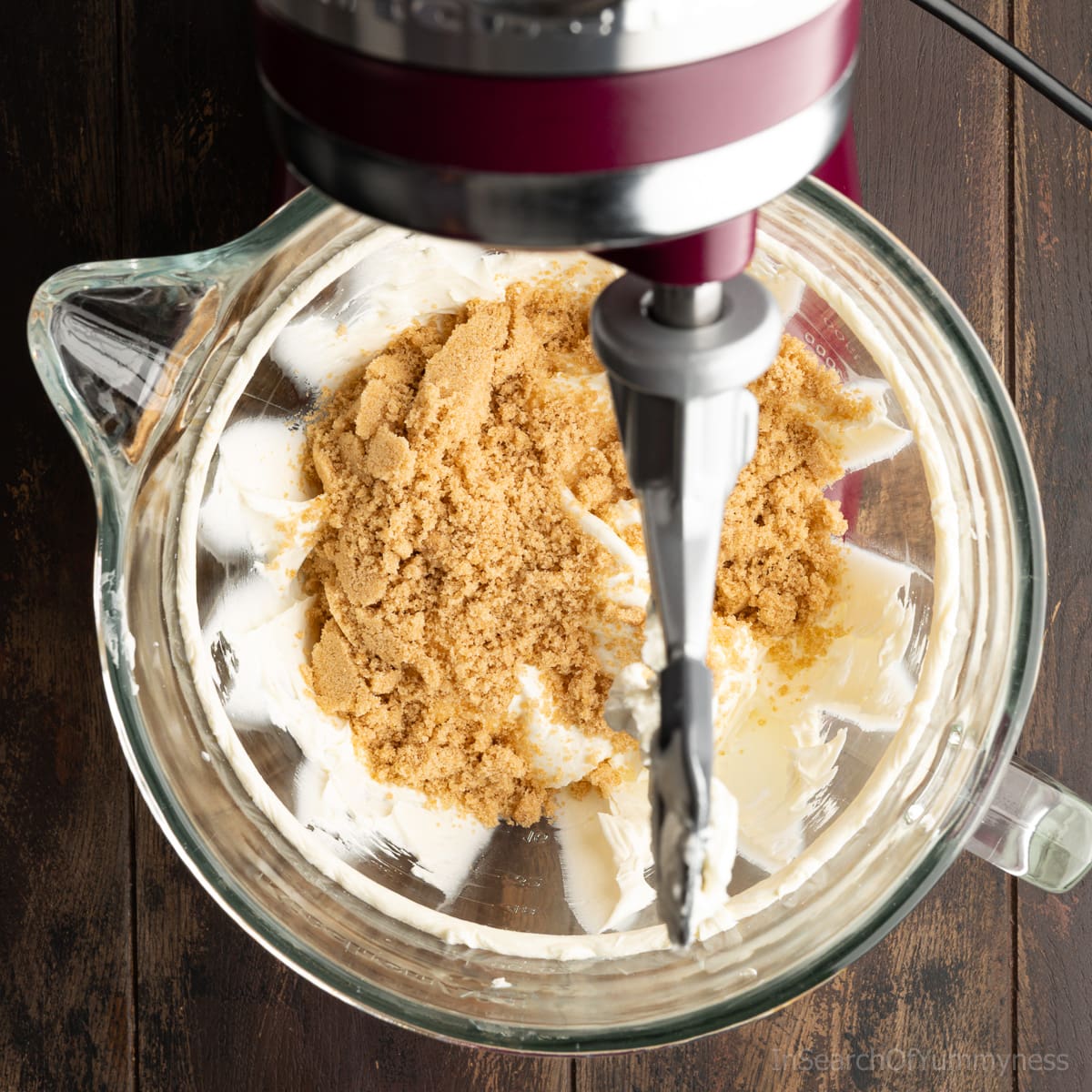 Light brown sugar and plain cream cheese in the mixing bowl of a KitchenAid stand mixer.