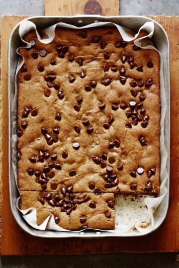 A parchment-lined baking tray full of pumpkin chocolate chip bars.