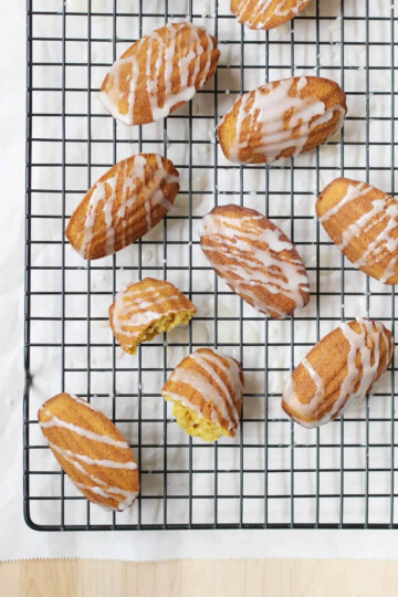 Nine pumpkin madeleines on a black cooling rack over a piece of parchment paper.
