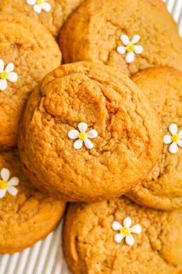 A pile of pumpkin spice cookies decorated with tiny white icing flowers.